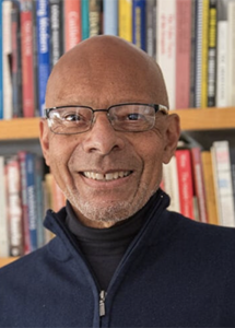 Man wearing glasses standing in front of a bookcase
