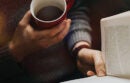 Person holding a coffee and reading a book