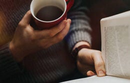Person holding a coffee and reading a book