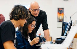 Three people working around a laptop and circuit