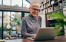 Cheerful mature businesswoman working on laptop at home office.