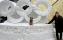 Man and dog pose with a snow sculpture of the Olympic rings