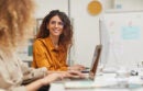 Two female colleagues chatting in an office