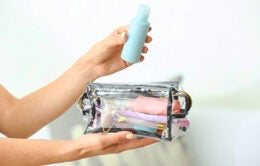 Female hands and cosmetics bag on light background