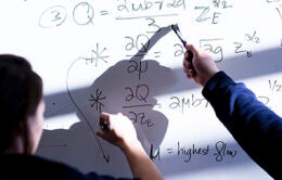 People doing math on a classroom whiteboard
