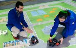 Researchers with model electric cars on a map board