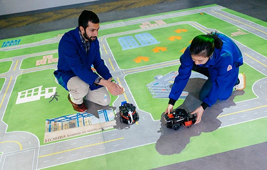 Researchers with model electric cars on a map board