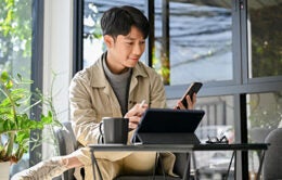 Happy and relaxed young Asian an using his phone and portable tablet at the coffee shop. remote working