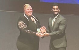 Two people standing on a stage; one handing another an awardCredit: Berkeley Lab