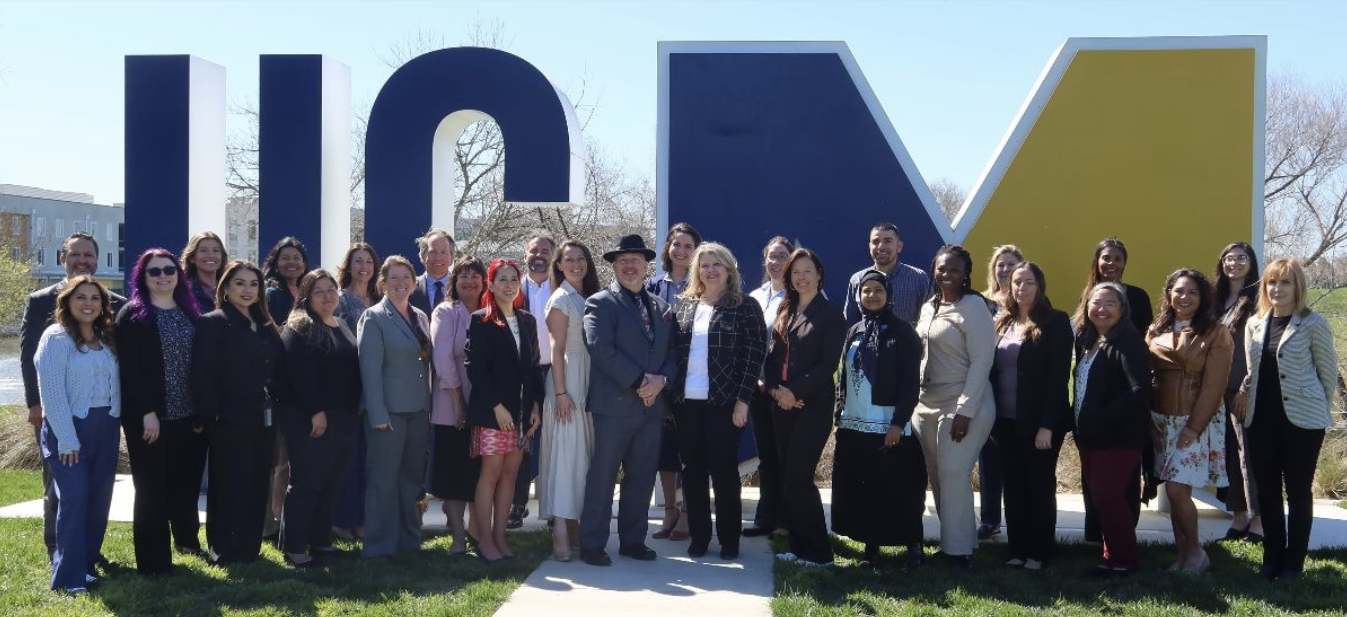 Group of people standing in front of the UC Merced sign