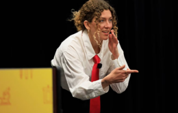 Woman in white shirt and red tie speaking to an off-camera audience