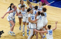 UCLA women's basketball team members come together on the court to celebrate their victory