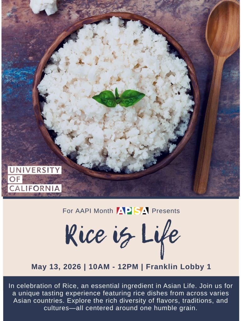 Wooden bowl of sticky rice with basil leaves on top next to a wooden spoon