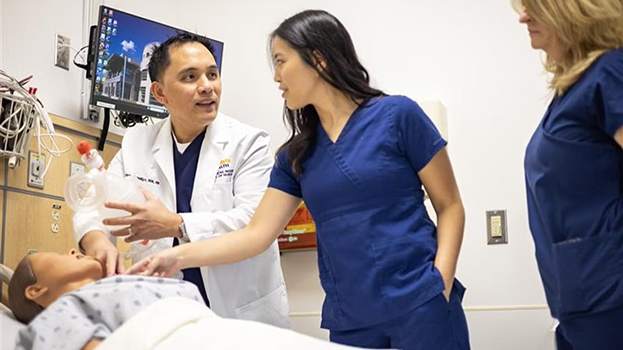 Man demonstrating nursing technique on plastic dummy