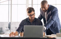 Manager helping employee with something on computer