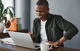Smiling young businessman using his laptop