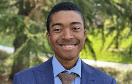 Isaiah outside on campus wearing a suit and tie