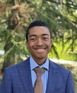 Isaiah outside on campus wearing a suit and tie