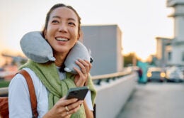 Woman traveling, smiling, holding phone at airport
