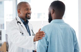 Doctor, black man and touch shoulder of patient for support, comfort and empathy in hospital.